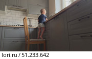 A Curious Young Child Engaging in an Exciting Exploration of the Kitchen from a Chair. Стоковое видео, видеограф Olesia Kondrateva / Фотобанк Лори