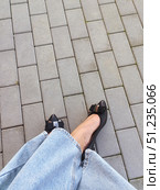 Stylish women's black leather shoes with a bow. legs in blue jeans on the street in the park. background for the design. Стоковое фото, фотограф Алёна Мостович / Фотобанк Лори