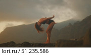 Beautiful woman dancing on cliffside at dusk with blurred background motion. Стоковое видео, видеограф Igor Tichonow / Фотобанк Лори