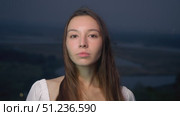 Depiction of lovely young woman in white gown, with dark eyes and flowing locks, against backdrop of night sky, outside urban area. Стоковое видео, видеограф Strunov David / Фотобанк Лори