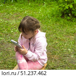 St.Petersburg,Russia-July 14,2025: A girl in colorful pink clothing looking at the smartphone on nature. Стоковое фото, фотограф Андрей Митин / Фотобанк Лори