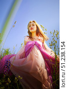 Beautiful woman in flowing pink dress stands in vibrant field under clear blue sky during sunny day. Стоковое фото, фотограф Кривошеина Елена Леонидовна / Фотобанк Лори