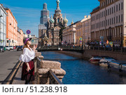 Church of the Resurrection of Christ (Spas-na-Krovi). A woman in a hat with a cigarette on the embankment in front of the church. Russia, St. Petersburg, August 15, 2025. Редакционное фото, фотограф Photojuli / Фотобанк Лори