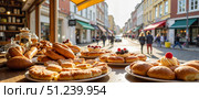 Baked goods displayed on a sunny street in a quaint town attracting passersby in the afternoon. Стоковое AI-изображение, AI-художник Ольга Невская / Фотобанк Лори