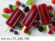 Berry juice popsicles in a plate on a white wooden table with fresh berries. Bright Ice pops with mint leaves and raspberries. Gut-health red pink berry popsicles. Inviting summer scene. Frozen treats. Стоковое AI-изображение, AI-художник Марина Демидюк / Фотобанк Лори