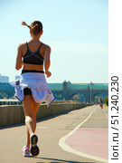 A woman runs on a track with a white jacket and black shorts.  Russia. Moscow. 24.08.25. Редакционное фото, фотограф Ярославский Максим / Фотобанк Лори