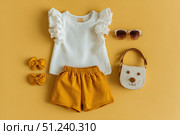 Fashion look of baby girl clothes and accessories. Set of muslin blouse, shorts, hairband and bag. Trendy cute tuff background for newborn. Toddler apparel. Female kid outfit. Pastel child wear set. Стоковое AI-изображение, AI-художник Марина Демидюк / Фотобанк Лори
