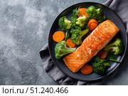 Steamed fish with with broccoli, carrot hot black pan. Baked salmon gray background. Paleo, keto, lshf, or dash diet. Fish and vegetables. Oven dish, gluten free, clean eating, balanced healthy food. Стоковое AI-изображение, AI-художник Марина Демидюк / Фотобанк Лори