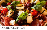 Delicious italian salad with prosciutto, mozzarella, and balsamic glaze. Стоковое фото, фотограф David Kashakhi / Фотобанк Лори