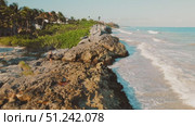 Woman walks on rocky shore path beside Caribbean Sea under morning light in Tulum, Mexico. Стоковое видео, видеограф Igor Tichonow / Фотобанк Лори