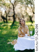 A woman is peacefully sitting at a lovely table nestled in the grass. Стоковое фото, фотограф Cantemir Dumitru / Фотобанк Лори