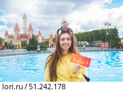 Москва, Россия. 4 сентября 2025 года. Девочка-подросток или молодая женщина с ободком с игрушечной капибарой на голове. Девушка держит билет в парк развлечений «Остров мечты» перед Замком, входом в парк.. Редакционное фото, фотограф Яна Проничева / Фотобанк Лори