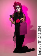 Woman in Calavera Makeup Shops for Day of the Dead on Pink Backdrop. Стоковое фото, фотограф Ольга Коваленко / Фотобанк Лори