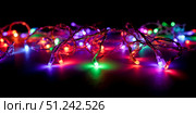Tangled pile of colorful Christmas lights with reflection on floor, festive holiday abstract background isolated on pure black for overlay. Стоковое AI-изображение, AI-художник Павел Муравьев / Фотобанк Лори