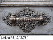 Antique Door Knob. Ornate wooden door with intricate carving metal handle. Faded gray wood. Elaborately fancy cabinet. Old furniture. Traditional architecture design. Decorative wrought iron metalwork. Стоковое AI-изображение, AI-художник Марина Демидюк / Фотобанк Лори