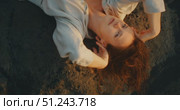 Woman lying on black volcanic rocks in relaxed pose with soft golden sunlight. Стоковое видео, видеограф Ольга Сухарева / Фотобанк Лори
