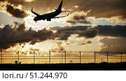 Passenger airplane landing at sunset over airport fence. Стоковое видео, видеограф Mikhail Davidovich / Фотобанк Лори
