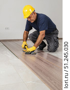 Skilled worker measuring wooden flooring in home renovation, craftsmanship. Стоковое AI-изображение, AI-художник Ольга Невская / Фотобанк Лори