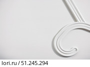 Part of a white clothes hanger on a white wooden background. Top view, copy space for text. Стоковое фото, фотограф Зарифа Арсланова / Фотобанк Лори