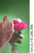 Hand Holds Perfume Bottle in Front of Vibrant Roses on Green Background. Стоковое видео, видеограф Ольга Коваленко / Фотобанк Лори
