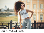 portrait of a girl in jeans and a t-shirt on the background of the building in the evening on a summer day. street dancing in the city. Стоковое фото, фотограф Арзюков Вадим Николаевич / Фотобанк Лори