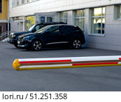A black car is parked in front of a white and red barrier. Russia. Moscow. 05.09.25. Редакционное фото, фотограф Ярославский Максим / Фотобанк Лори