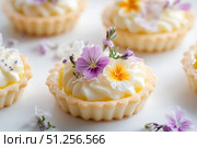 Delicate Edible Flower Tarts with Creamy Frosting and Sophisticated Presentation Ideal for Celebrations and Gatherings. Стоковое AI-изображение, AI-художник Башкирова Анна / Фотобанк Лори