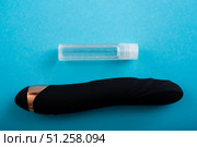 Top view of a black dildo and a bottle of lubricant on a blue background. Стоковое фото, фотограф Михаил Решетников / Фотобанк Лори