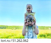Children enjoying a playful moment outdoors in a sunny field surrounded by blooming flowers. Стоковое фото, фотограф Кривошеина Елена Леонидовна / Фотобанк Лори