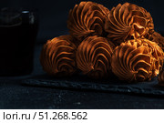 Coffee Zephyr with intricate swirls, elegantly arranged on a dark slate plate, accompanied by a glass of coffee, creating a rich and inviting atmosphere for culinary delight. Стоковое фото, фотограф Ирина Ручушкина / Фотобанк Лори