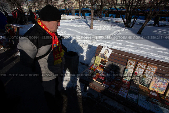 23.02.2023, Москва. Акция КПРФ по случаю 105-й годовщины Рабоче-Крестьянской Красной Армии и в поддержку специальной военно-политической операции Российской Армии. Мужчина рассматривает книги, которые продают рядом с местом проведения акции. Редакционное фото, фотограф Дмитрий Киселёв / Фотобанк Лори