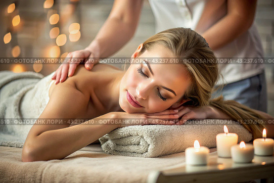 A banner for professional massage parlors. A young, beautiful blonde woman enjoys a massage in a modern spa by candlelight. Relaxation and harmony, body care. Стоковое AI-изображение, AI-художник Photojuli / Фотобанк Лори