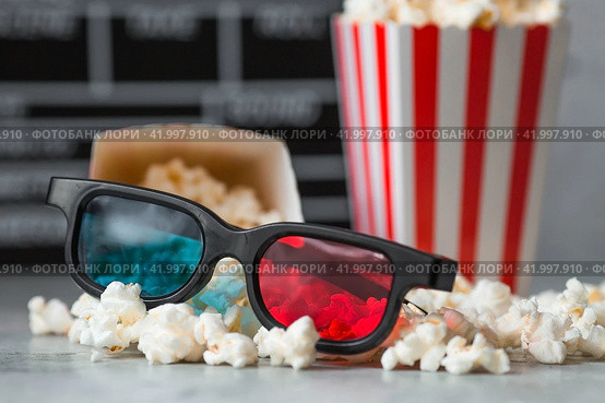 A banner for the film industry. A movie date. A movie camera, 3D glasses, popcorn in striped cups on a stylish concrete gray background. The premiere of the film. (2024 год). Стоковое фото, фотограф Photojuli / Фотобанк Лори