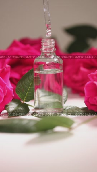 A Beautiful Rose Essence Dropper Bottle Elegantly Surrounded by Live Petals and Leaves. Стоковое видео, видеограф Ольга Коваленко / Фотобанк Лори