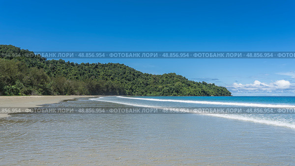 A beautiful tropical beach without people. The waves of the turquoise ocean foam and spread over the sand. Green vegetation on the hill. Blue sky, clouds. Copy space. Malaysia. Borneo. Kota Kinabalu. Стоковое фото, фотограф Вера Ивановна Кубарева / Фотобанк Лори
