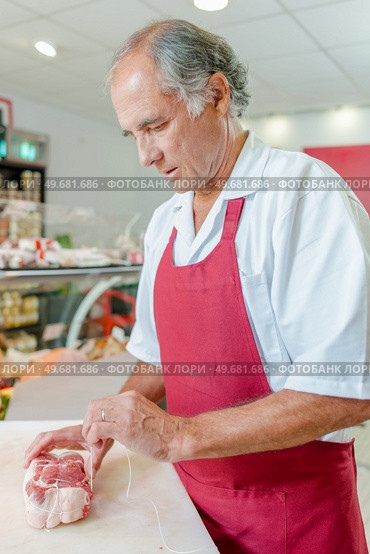 a butcher is preparing meat. Стоковое фото, агентство Ingram Publishing / Фотобанк Лори
