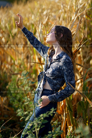 A captivating and enchanting portrait of a young woman dressed in a stylish outfit, gracefully posing amidst the vibrant golden cornfields, beautifully merging the elements of nature and fashion. An Elegant Portrait Captured in a Beautiful Cornfield During the Enchanting Golden Hour. Стоковое фото, агентство Ingram Publishing / Фотобанк Лори