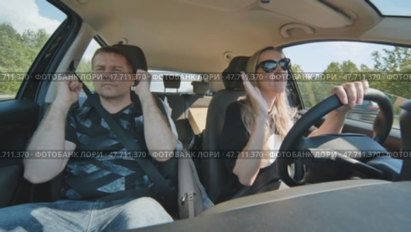 A cheerful man and woman sing and dance in the car while driving. Стоковое видео, видеограф Mikhail Davidovich / Фотобанк Лори