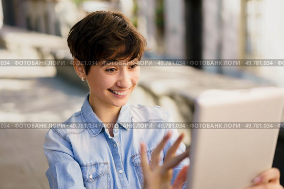 A cheerful young woman enjoys a video call outdoors, embodying joy and connection. Her warm expression reflects a relaxed lifestyle, showcasing how technology fosters friendships amidst nature. A Cheerful Young Woman Engaged in an Enjoyable Video Call While Outdoors in Daylight. Стоковое фото, агентство Ingram Publishing / Фотобанк Лори