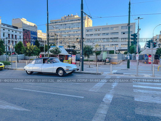 A classic white car is on a city street in front of modern and neoclassical buildings (2023 год). Редакционное фото, фотограф Виктор Ветошкин / Фотобанк Лори