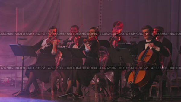 A classical music ensemble performs under soft lighting, showcasing musicians poised with violins and a cello. The stage atmosphere exudes elegance and professionalism. Russia, January 1, 2025. Редакционное видео, видеограф Воловодов Владимир / Фотобанк Лори
