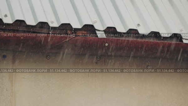 A close-up of a metal roof over which torrential rain flows down into a storm drain. Slow motion shooting of rain. Стоковое видео, видеограф Воловодов Владимир / Фотобанк Лори