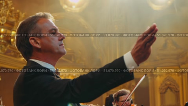 A conductor directs a symphony orchestra in a performance. Стоковое AI-видео, аниматор Данила Большаков / Фотобанк Лори