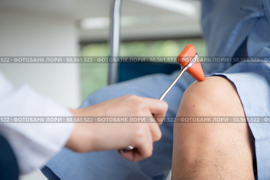 A doctor uses a reflex hammer to evaluate a patient’s knee joint. Стоковое фото, агентство Ingram Publishing / Фотобанк Лори