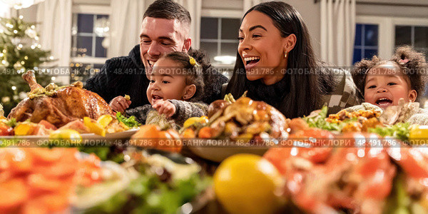 A family of four is gathered around a table full of food. Стоковое AI-изображение, AI-художник Ярославский Максим / Фотобанк Лори