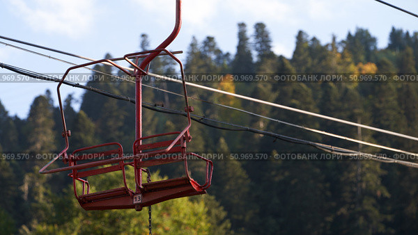 A fragment of the cable car. The two-seater chairlift number 13 in the air against the backdrop of picturesque autumn mountains. Стоковое фото, фотограф Роман Дзюбало / Фотобанк Лори