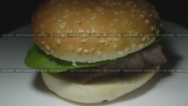 A fresh burger bun with a piece of fried pork and greens on a white plate. Стоковое видео, видеограф Ярославский Максим / Фотобанк Лори