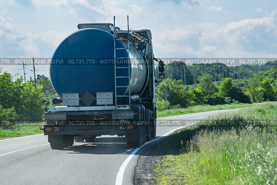 A fuel truck with a blue tanker drives along a country asphalt road. Стоковое фото, фотограф Антон Вахрушев / Фотобанк Лори