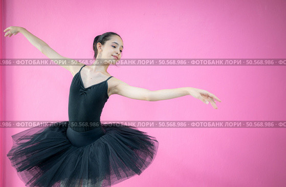 A girl ballet student practices ballet dancing at home with a white background. Стоковое фото, агентство Ingram Publishing / Фотобанк Лори