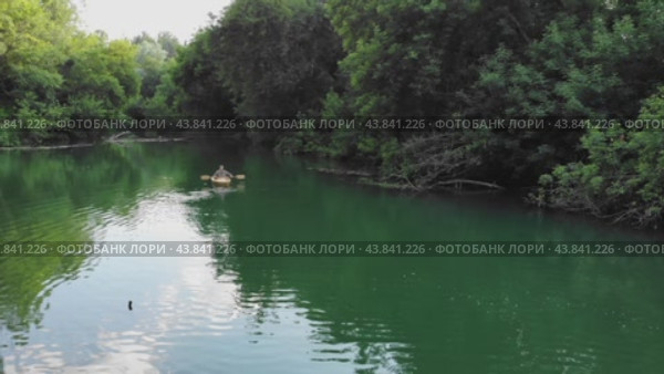 A girl in a small boat tries to steer it by using an oar to navigate down the river (2024 год). Редакционное видео, видеограф Strunov David / Фотобанк Лори